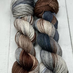 May include: Two skeins of yarn, one brown and gray with white stripes, and one blue and gray with white stripes.