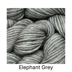 May include: Close-up of gray yarn skeins. The yarn is a light, solid gray color, with a thick, textured appearance. The text "Elephant Grey" is displayed at the bottom of the image. This yarn is suitable for various knitting and crochet projects.