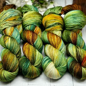 May include: Five skeins of yarn in a green, brown, and yellow colorway. The yarn is hand-dyed and has a variegated pattern.