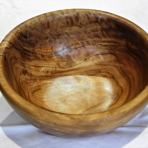 Può includere: Una grande ciotola rotonda in legno con una finitura in legno naturale. La ciotola ha un'apertura larga e poco profonda e un interno liscio e lucido.