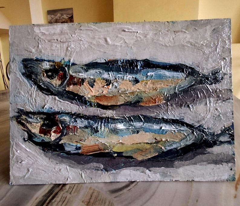 May include: Oil painting of two fish, rendered with thick brushstrokes. The fish are primarily blue, with accents of orange, brown, and white. The background is a textured, light gray. The artwork has a rustic, impressionistic style.