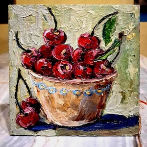 Puede incluir: Pintura al óleo de un cuenco lleno de cerezas rojas maduras. El cuenco es de color marrón claro con un diseño floral azul y blanco en el borde. El fondo es texturizado en tonos verdes y beige.