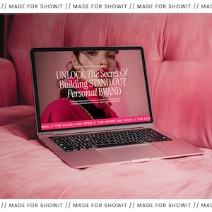 May include: A pink laptop displaying the text "UNLOCK The Secret Of Building STAND OUT Personal BRAND" on a pink velvet surface. The laptop is open, revealing a website with a woman in a pink outfit. The background is a pink velvet sofa.