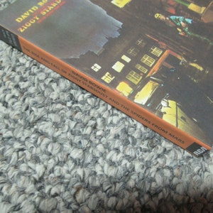 May include: The cover of David Bowie's album, "The Rise and Fall of Ziggy Stardust and the Spiders from Mars." The artwork is dark with gold and white text. The RCA logo is in the bottom right corner.