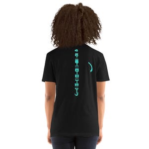 Könnte beinhalten: Schwarzes T-Shirt mit einem türkisfarbenen Grafikdesign auf dem Rücken. Das Design umfasst eine vertikale Reihe abstrakter Formen und eine gebogene Linie. Das Shirt besteht aus weichem Material und hat kurze Ärmel.