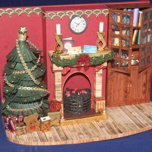 May include: A miniature papercraft Christmas scene with a fireplace, a decorated Christmas tree, a bookcase, and presents under the tree.