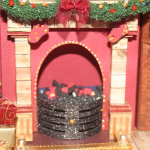 May include: A miniature fireplace with a red brick facade, a green garland with red berries and a red bow, and a black metal fire grate with glowing embers.