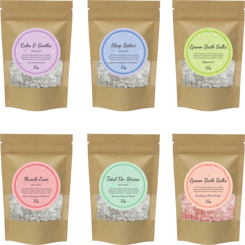 May include: Six brown paper pouches with white bath salts inside. Each pouch has a round label with a different color and scent. The labels read: Calm & Soothe, Sleep Better, Epsom Bath Salts, Muscle Ease, Total De-Stress, and Epsom Bath Salts. Each pouch contains 35g of bath salts.