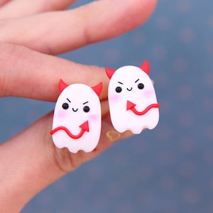 May include: A pair of white ghost earrings with red devil tails. The ghosts have cute, smiling faces.