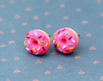 May include: A pair of pink donut stud earrings with colorful sprinkles.
