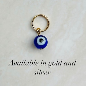 May include: A gold charm with a blue evil eye bead. Available in gold and silver.