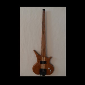 May include: A brown wooden bass guitar with a unique body shape and a black pickguard. The guitar has a single pickup and a set of tuning keys.