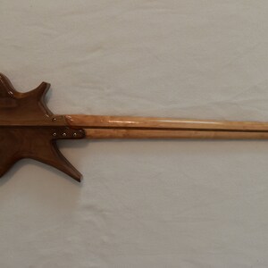 May include: A brown and natural wood electric bass guitar with a unique body shape and a long neck.