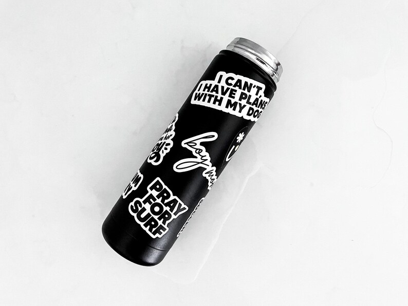 A black insulated water bottle with various stickers on it, including one that says "I CAN'T I HAVE PLAN WITH MY DOG".