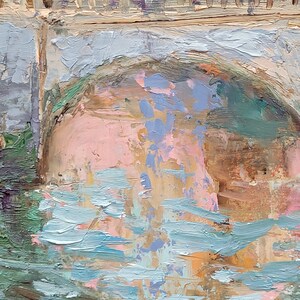 May include: Impressionistic oil painting of a bridge over water. The bridge is painted in shades of gray and beige, with a pink and blue arch. The water is depicted with blue and green brushstrokes, creating a textured effect.
