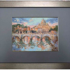 May include: Oil painting of a cityscape with a large domed building, possibly a cathedral, and a bridge over a river. The artwork is framed in a silver-toned frame with a gray mat.