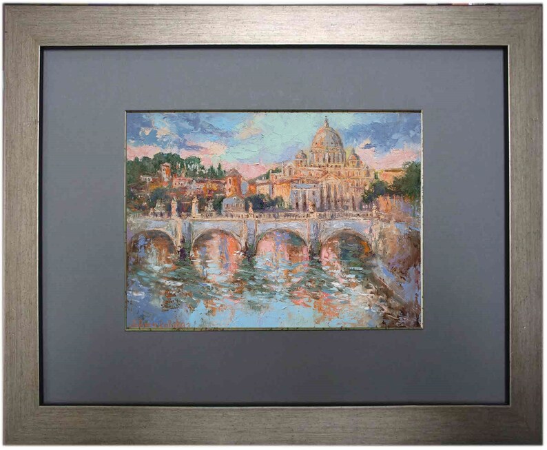 May include: Oil painting of a cityscape with a large domed building, possibly a cathedral, and a bridge over a river. The artwork is framed in a silver-toned frame with a gray mat.
