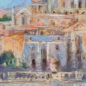 May include: Oil painting of a European cityscape with buildings in shades of beige, orange, and gray. The artwork features a dome and architectural details, with a light blue sky in the background. The brushstrokes are visible, creating a textured effect.