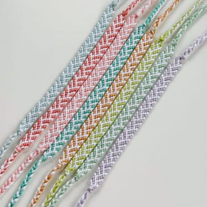 May include: A collection of colorful friendship bracelets. Each bracelet features a chevron pattern in a different color, including red, teal, orange, green, and purple. The bracelets are made of woven thread.