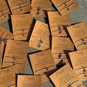 May include: A collection of friendship bracelets with charms and the text "No matter where we go, No matter what we do, You'll always be there for me and I'll always be there for you. One for you." on brown cardstock.