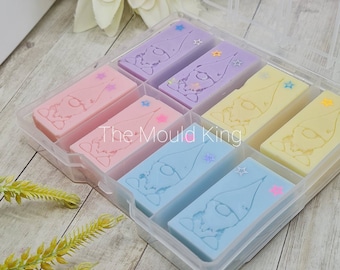 May include: A clear plastic storage box with six compartments filled with colorful, hand-poured gnome-shaped wax melts. Each melt has a different color and glitter accents. The box is labeled "The Mould King."