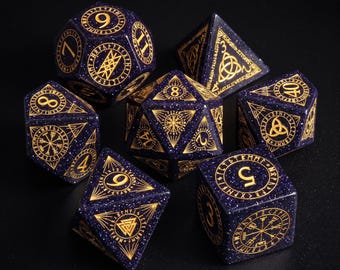 Peut inclure: Un ensemble de sept dés polyédriques bleu profond avec des paillettes dorées et des gravures à l'encre dorée. Chaque dé présente des motifs géométriques complexes, des symboles runiques et des chiffres clairs. La collection comprend diverses formes comme d20, d12, d10, d8, d6 et d4, avec une esthétique céleste cohérente.