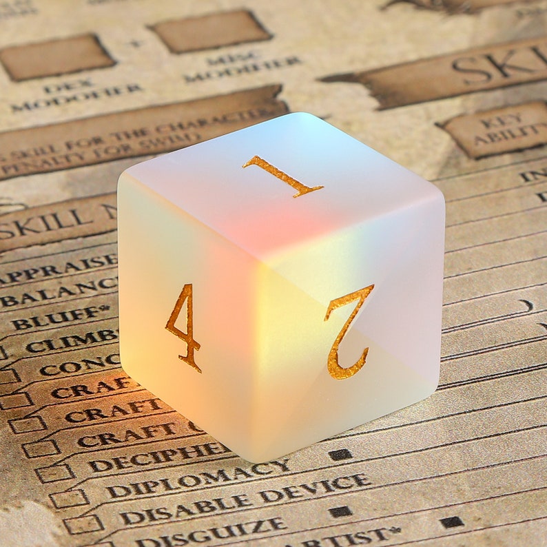 May include: A translucent, square-shaped die with gold-colored numbers 1, 2, and 4 visible. The die has a rainbow-like effect on its surface. The background features a character sheet with text including "SKILL" and "DEX MODIFIER".