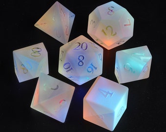 May include: Set of seven iridescent dice with numbers 1 through 20. The dice are made of a translucent material and glow in the dark.