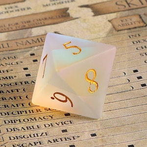 May include: A frosted, iridescent D20 die with gold-colored numerals. The die is set against a backdrop of a role-playing game character sheet. The numbers 1, 5, 8, and 9 are visible.
