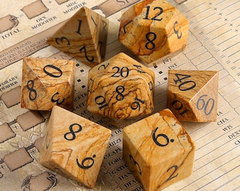 Peut inclure: Un ensemble de six dés avec une finition en pierre naturelle. Les dés sont numérotés 4, 6, 8, 12, 20 et 60. Les dés sont sur une surface brune avec un motif en grille.