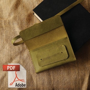 May include: A green leather wallet with a flap closure and a single slot on the front. The wallet is lying on a brown burlap surface.