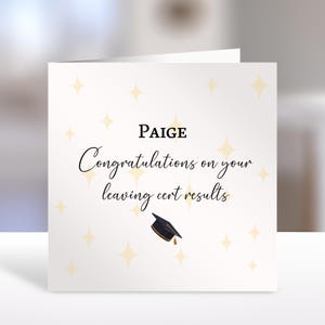 Puede incluir: Una tarjeta de felicitación cuadrada de color blanco con el nombre Paige en texto negro, seguido del texto en cursiva negra Congratulations on your leaving cert results, con un birrete de graduación azul oscuro y estrellas amarillas.