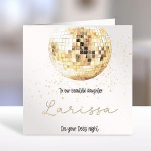 Peut inclure: Une carte de vœux carrée illustrée d'une boule à facettes dorée avec des paillettes dorées éparpillées. Le texte indique : To our beautiful daughter, Larissa, On your Debs night. Le motif est présenté sur un fond blanc uni.