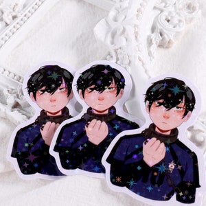 Peut inclure: Trois autocollants représentant un personnage de dessin animé aux cheveux noirs, portant une chemise bleu foncé avec un col blanc et une chaîne argentée. Le personnage a une expression sérieuse et tient ses mains jointes devant lui. L'arrière-plan des autocollants est bleu foncé avec un effet brillant.