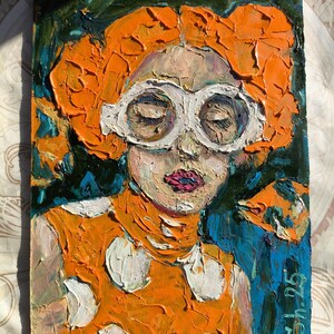 Pode incluir: Pintura a &oacute;leo de uma pessoa com cabelo laranja e &oacute;culos de arma&ccedil;&atilde;o branca. A pessoa est&aacute; vestindo uma blusa laranja com bolinhas brancas. O fundo &eacute; uma mistura de azul e verde. A pintura &eacute; assinada "Sh 25".
