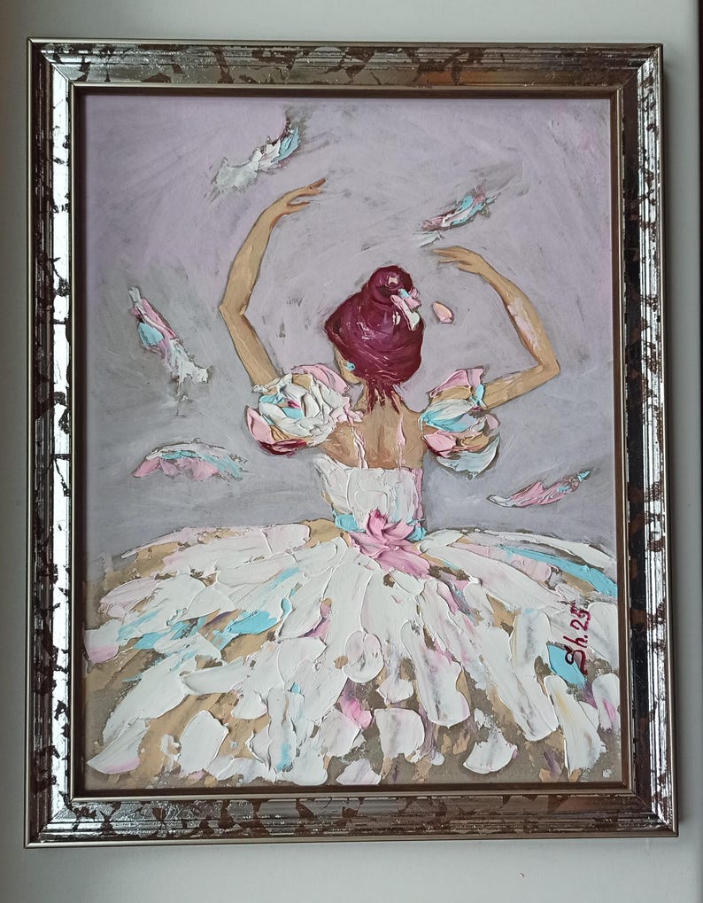 Pode incluir: Pintura a &oacute;leo de uma bailarina em um vestido branco com detalhes em rosa e azul, emoldurada em uma moldura prateada. O cabelo da bailarina &eacute; de um tom bord&ocirc; profundo e ela est&aacute; com os bra&ccedil;os para cima. O fundo &eacute; cinza suave com pinceladas.