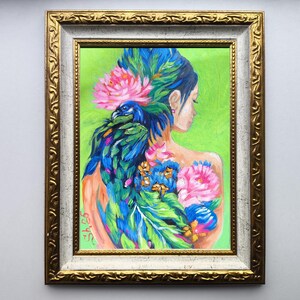 Pode incluir: Obra de arte emoldurada com as costas de uma mulher adornadas com um pav&atilde;o e desenhos florais. A pintura apresenta cores vibrantes, incluindo azul, verde, rosa e laranja, sobre um fundo verde. A moldura &eacute; dourada com uma borda interna branca.