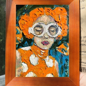 Pode incluir: Uma pintura a &oacute;leo numa moldura laranja retrata uma pessoa com cabelo laranja e &oacute;culos brancos. A pessoa usa um vestido laranja com bolinhas brancas. O fundo &eacute; azul e verde. A pintura est&aacute; assinada no canto inferior direito.