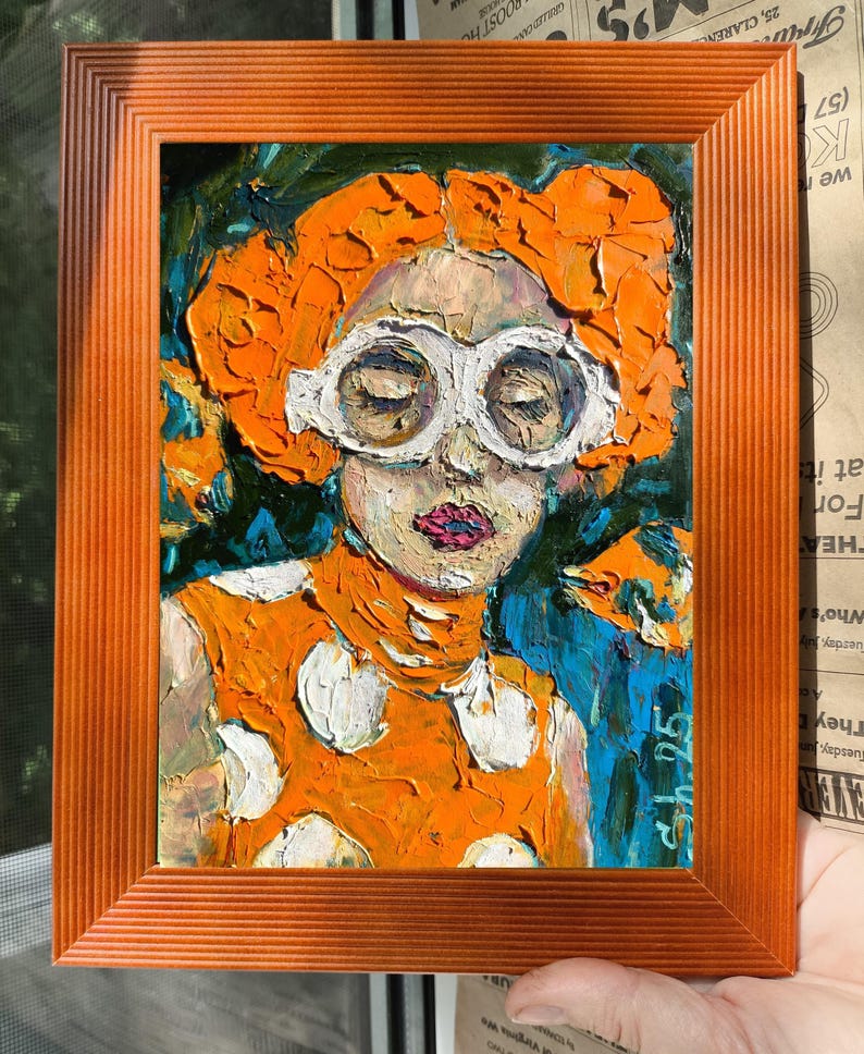 Pode incluir: Uma pintura a &oacute;leo numa moldura laranja retrata uma pessoa com cabelo laranja e &oacute;culos brancos. A pessoa usa um vestido laranja com bolinhas brancas. O fundo &eacute; azul e verde. A pintura est&aacute; assinada no canto inferior direito.