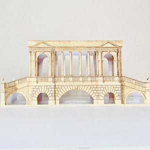 May include: A wooden model of a bridge with arches and columns. The bridge is made of light brown wood and has a white background.