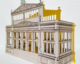 May include: A paper model of the Konzerthaus Berlin, a concert hall in Berlin, Germany. The model is made of white paper with brown and black details. The model is a 3D representation of the building, with a detailed facade and interior.