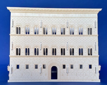 May include: A white paper model of a building with a large arched doorway and multiple windows. The building has a beige trim and is set against a blue background.