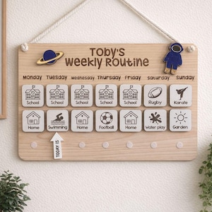 May include: A wooden weekly routine board with the text "Toby's weekly Routine". The board features icons for school, home, swimming, football, water play, and garden. A blue astronaut and a planet are attached to the board.
