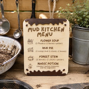 May include: A rectangular wooden sign with a jute rope hanger, featuring dark brown mud-like accents at the top and bottom. The text reads: MUD KITCHEN MENU, FLOWER SOUP, MUD PIE, FOREST STEW, and MAGIC POTION, accompanied by small icons and recipes.