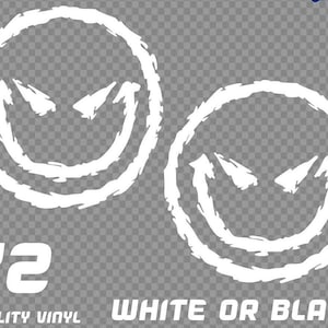 May include: Two white vinyl stickers with a distressed smiley face design. The face has pointed eyes and a jagged smile. The text reads "X2 QUALITY VINYL WHITE OR BLACK". The stickers are designed for application.
