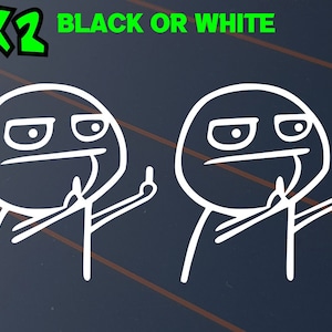 May include: Two white meme-style stickers featuring a face with a raised middle finger. The text "X2" is in green, and "BLACK OR WHITE" is in green above the images. The stickers are on a dark blue background.