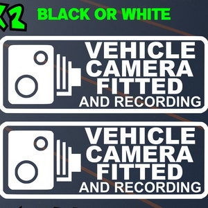 May include: Two white rectangular stickers with the text "VEHICLE CAMERA FITTED AND RECORDING". The stickers also feature a graphic of a camera. The text "BLACK OR WHITE" is above the stickers.