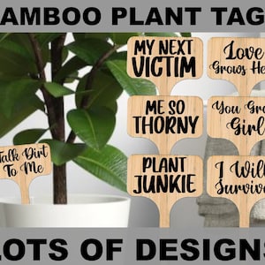 May include: Wooden bamboo plant tags with black text, such as "My Next Victim" and "Love Grows Here." The tags are displayed in a plant pot. The image also includes the text "Talk Dirt To Me" and "LOTS OF DESIGNS" at the bottom.