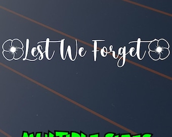 May include: White cursive text on a dark blue background reads "Lest We Forget" with a poppy flower on each side. Below, in green block letters, it says "MULTIPLE SIZES".