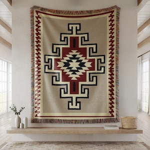 Può includere: Un arazzo tessuto da appendere alla parete con un motivo geometrico in tonalità di rosso, nero, bianco e beige. L'arazzo ha un bordo a frangia.